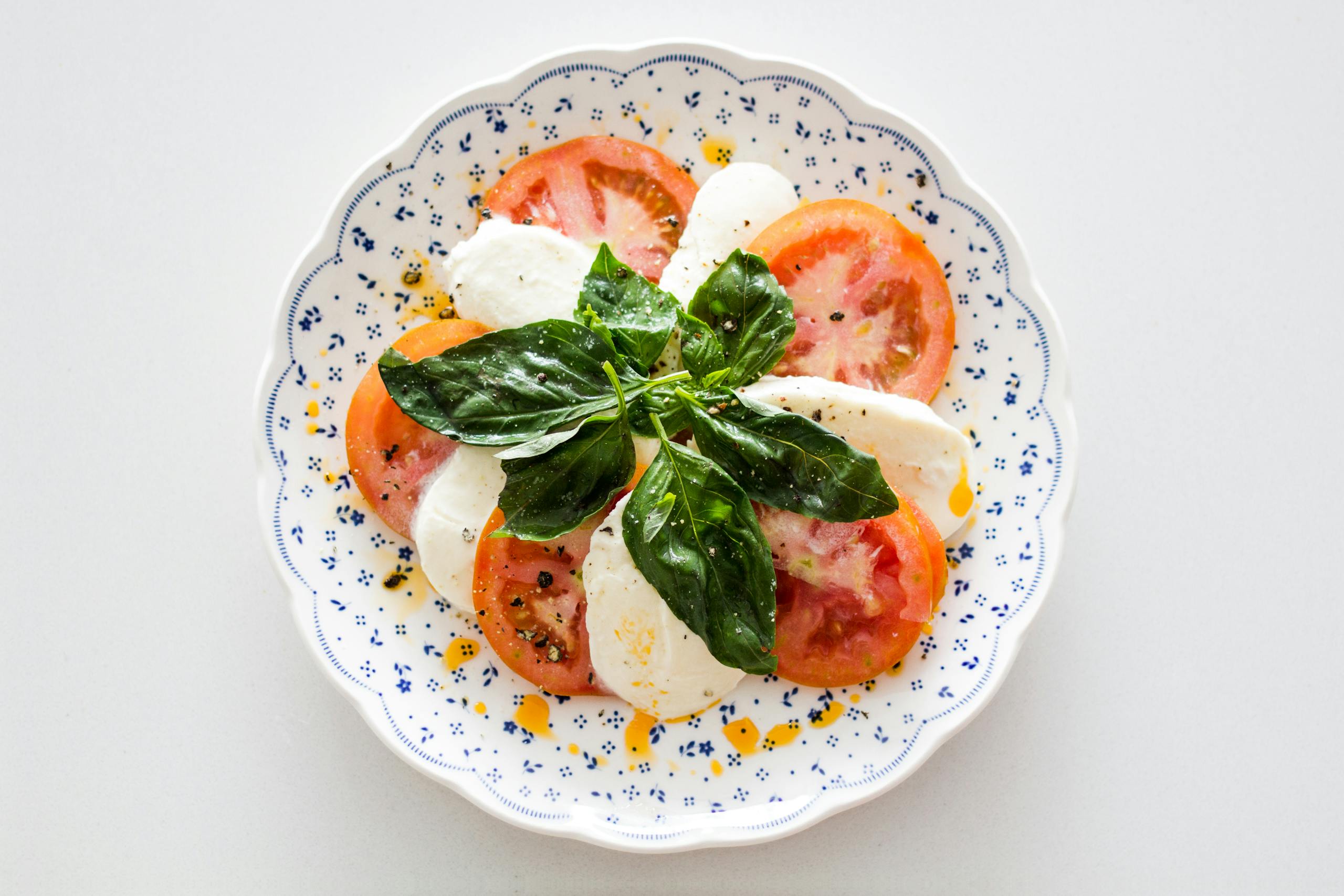 Fresh Caprese salad with tomatoes, mozzarella, and basil on a decorative plate.