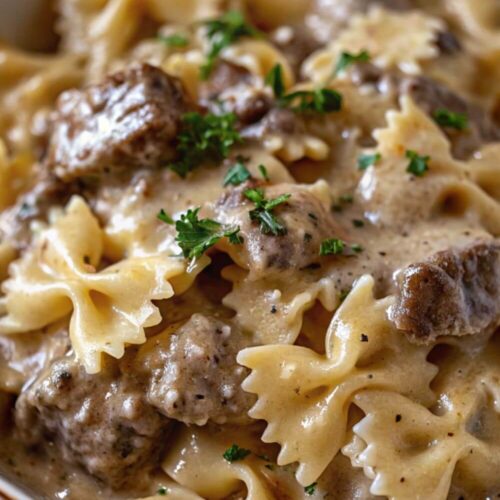 Bowl of bowtie pasta with beef in a creamy sauce.