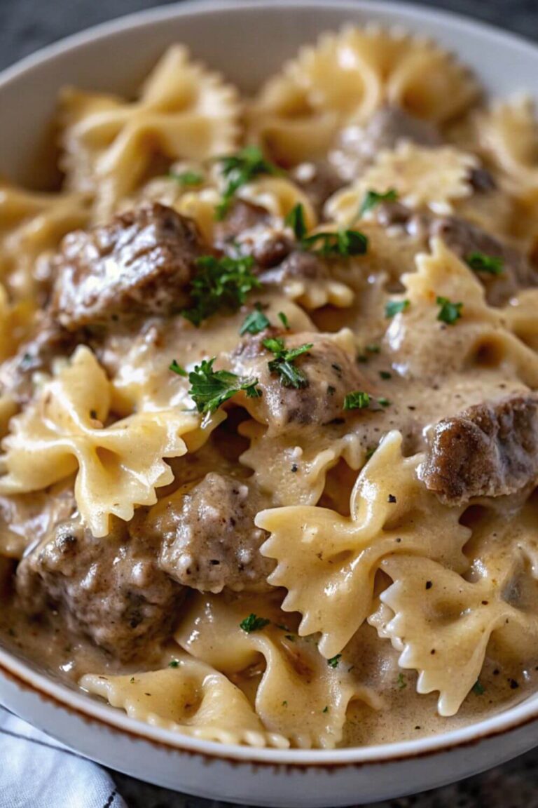 Bowl of bowtie pasta with beef in a creamy sauce.